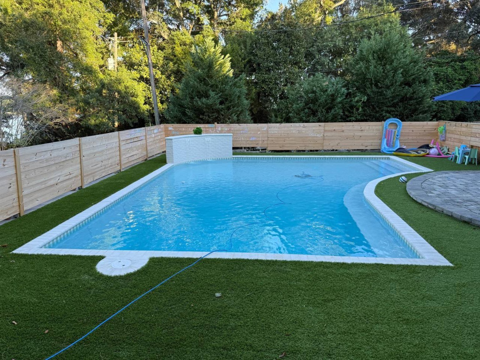 Freeform custom pool with white raised wall and turf edge
